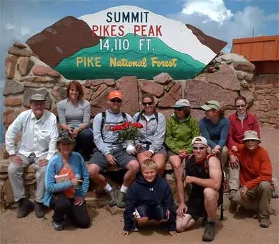 Julie with family and friends at the 14,110-foot summit sign on Pikes Peak